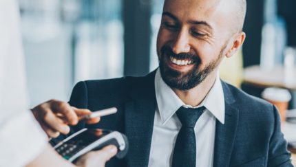 man in suit paying with digital card on mobile phone