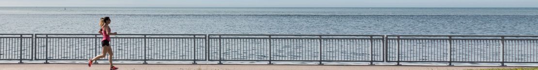 Woman jogging on the boardwalk by the water