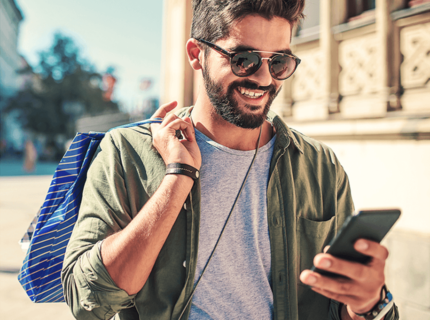 man wearing sunglasses and holding phone outside